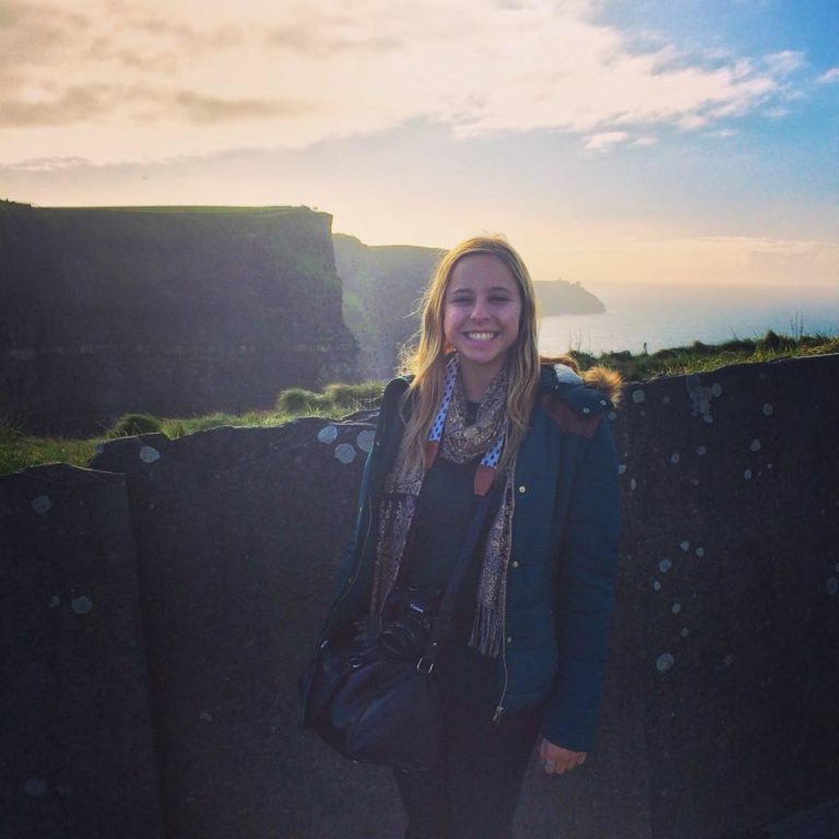 Woman smiling in front of the Cliffs of Moher, Ireland