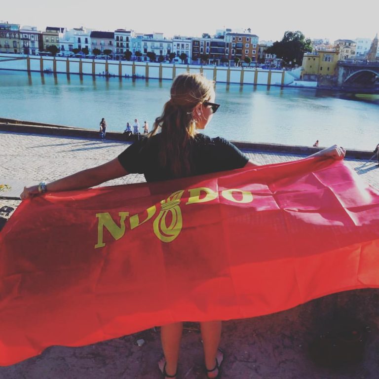 Woman holding a Sevilla flag alongside a river in Sevilla, Spain