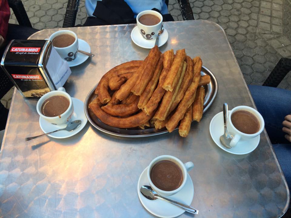 Dessert in Sevilla: churros on a plate with five mugs of chocolate on a table