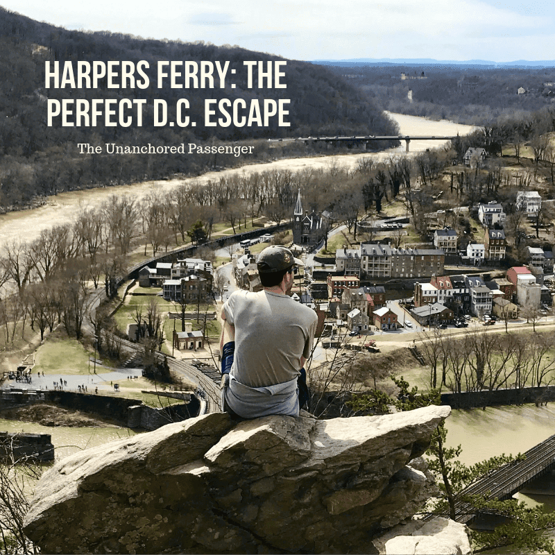 Man sitting on a rock overlooking a town with the text "Harpers Ferry: The Perfect D.C. Escape"