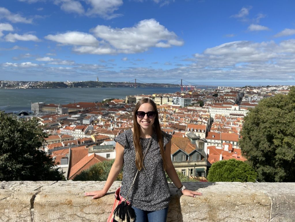 Woman standing in front of the city of Lisbon and river down below