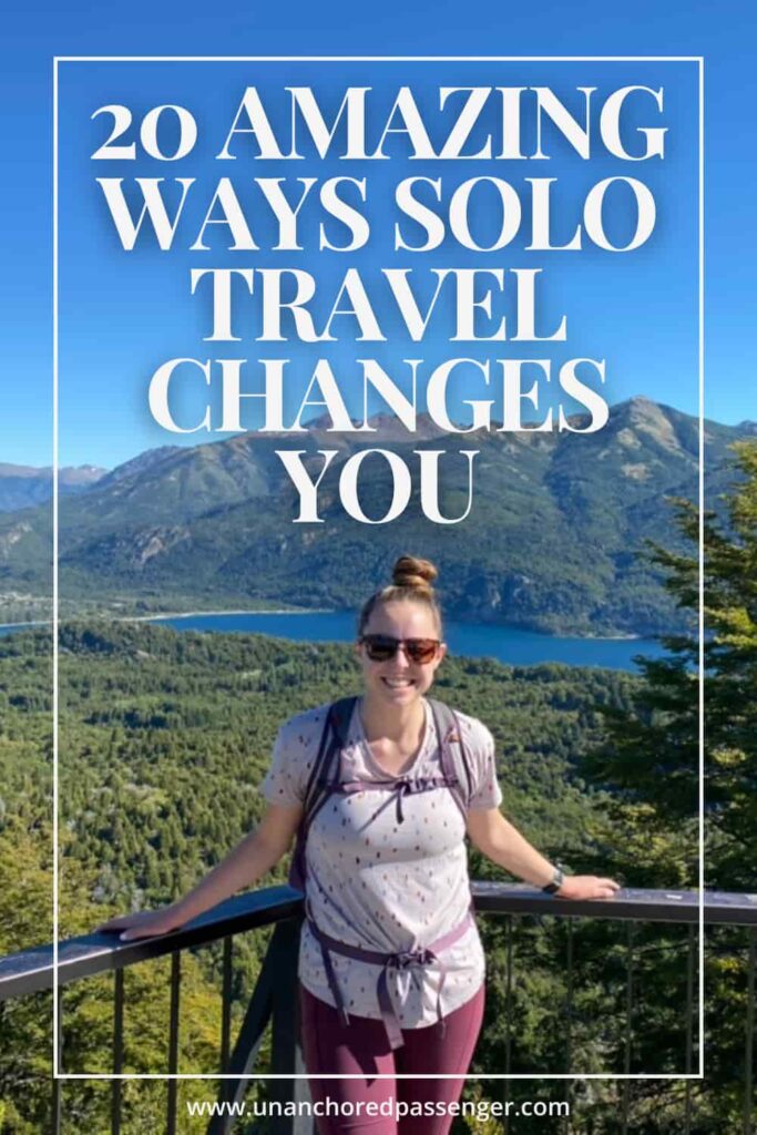 Woman smiling at an overlook of a bright blue lake surrounded by mountains in Bariloche, Argentina with text that says, "20 amazing ways solo travel changes you"