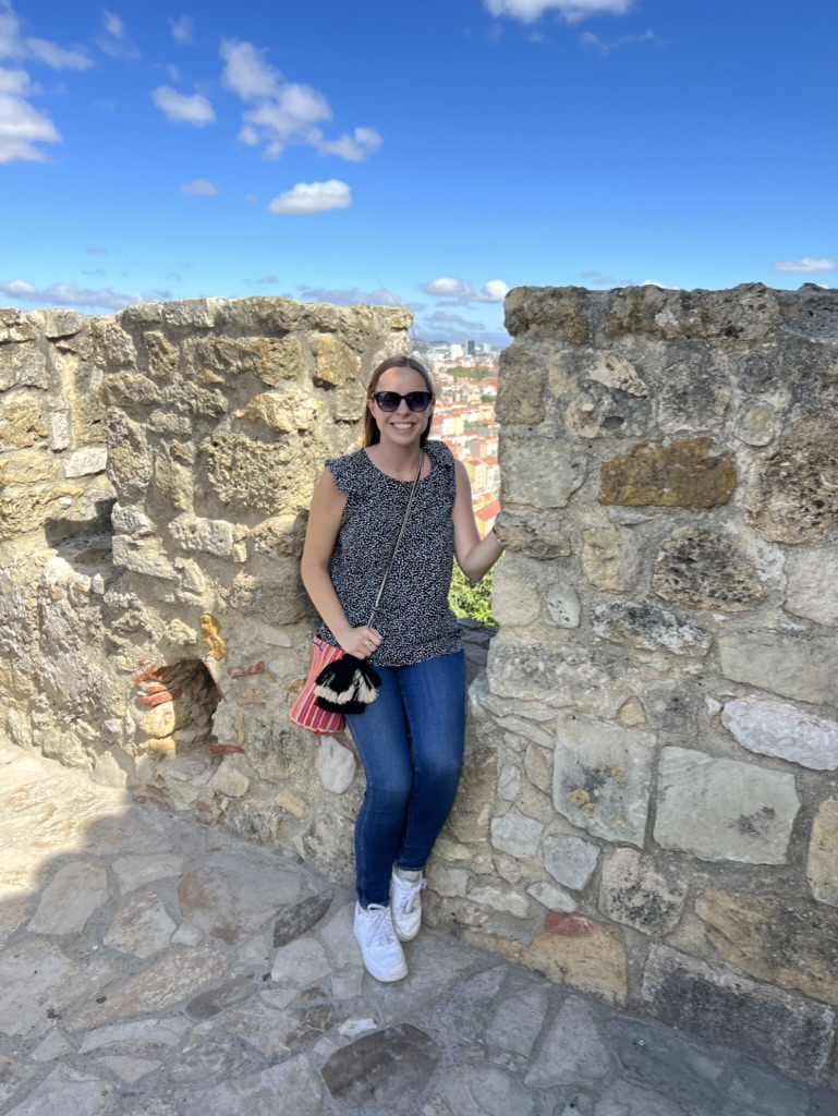 Woman smiling sitting on a castle wall at Castelo de São Jorge in Lisbon, Portugal