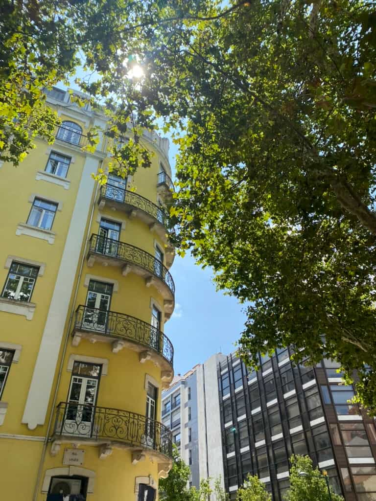 Ornate yellow building and a large tree in Lisbon, Portugal