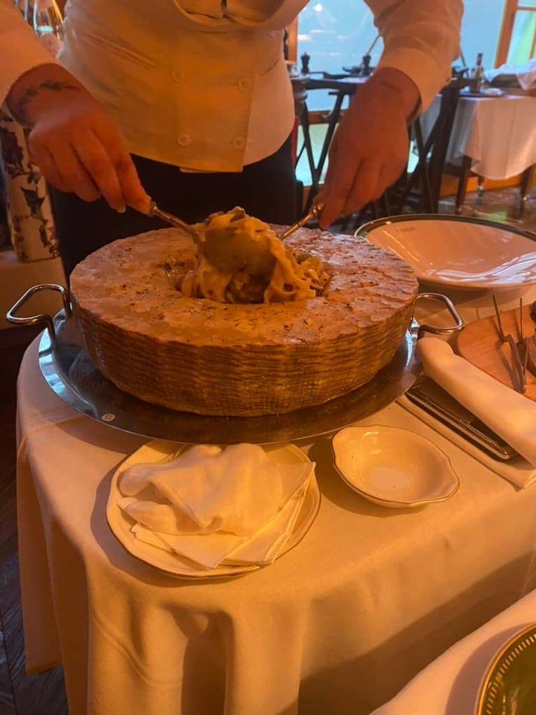 Waiter stirring up pasta within a large parmesan cheese wheel at Rocco in Lisbon, Portugal