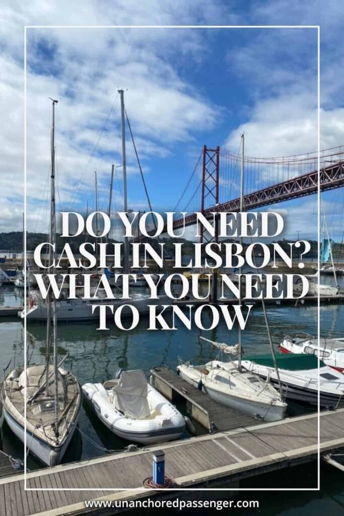 Boats docked in front of the 25 de Abril Bridge in Lisbon, Portugal with text that says, "Do You Need Cash in Lisbon? What You Need to Know"