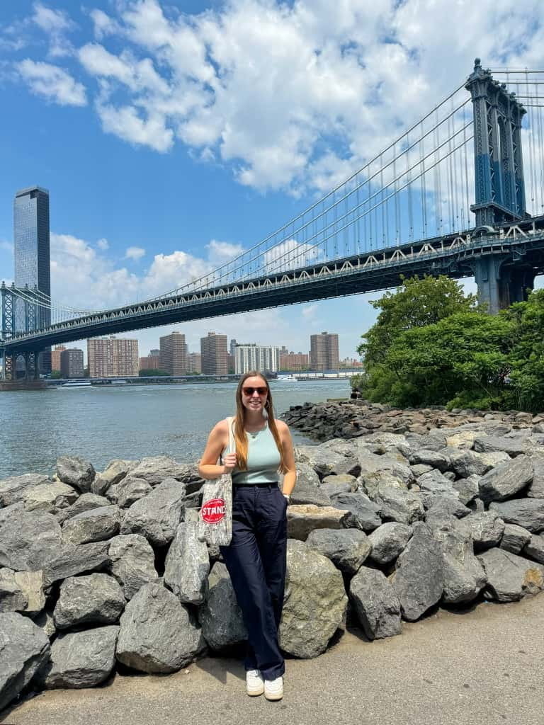 Woman smiling in front of the Manhattan Bridge in Brooklyn, New York