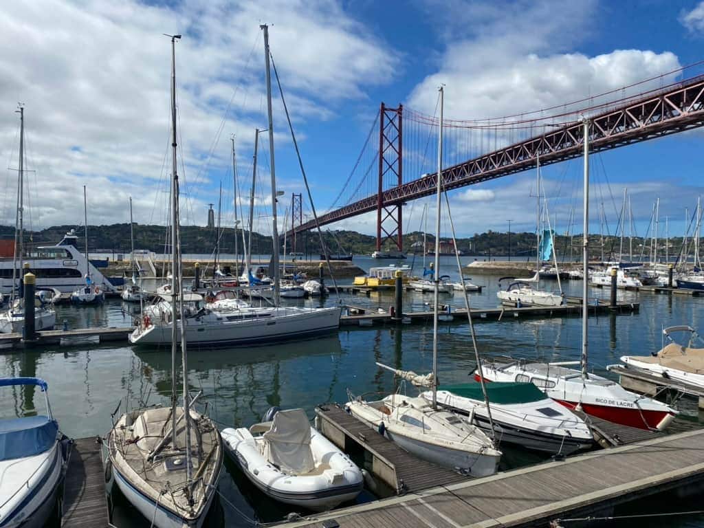 Boats docked in front of the 25 de Abril Bridge in Lisbon, Portugal