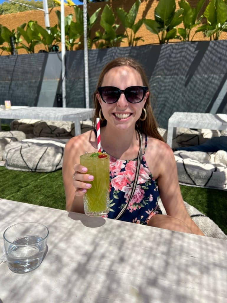 Woman smiling with a drink on a rooftop bar in Lisbon, Portugal