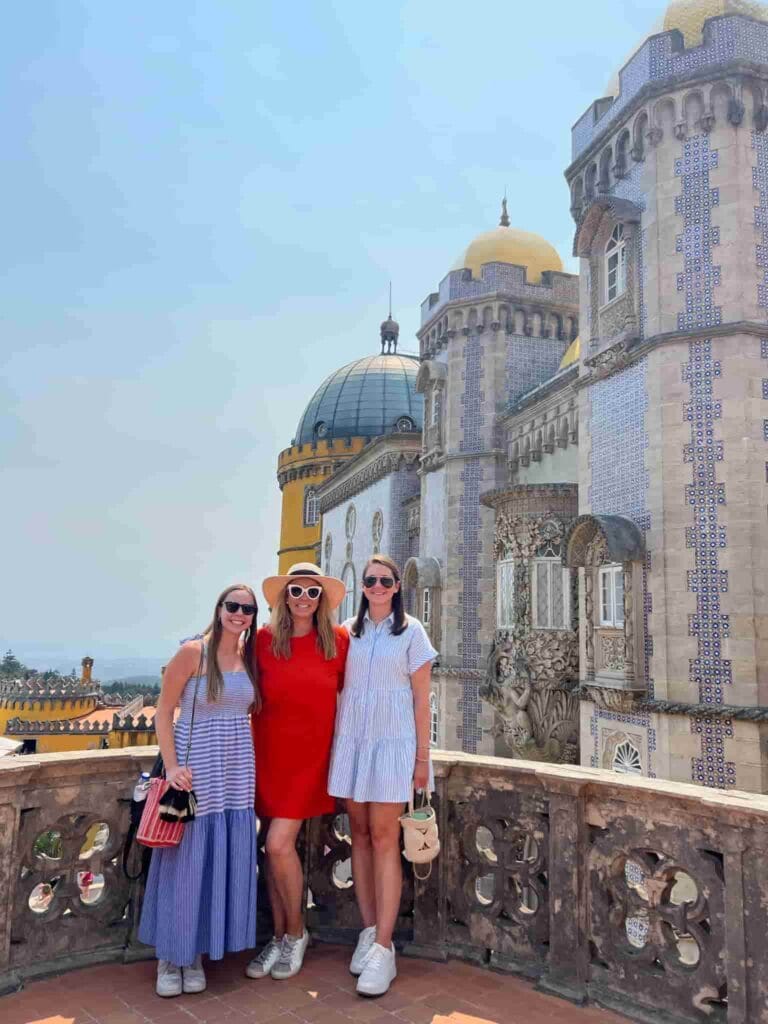 Three women smiling in front of Pena Palace in Sintra, Portugal