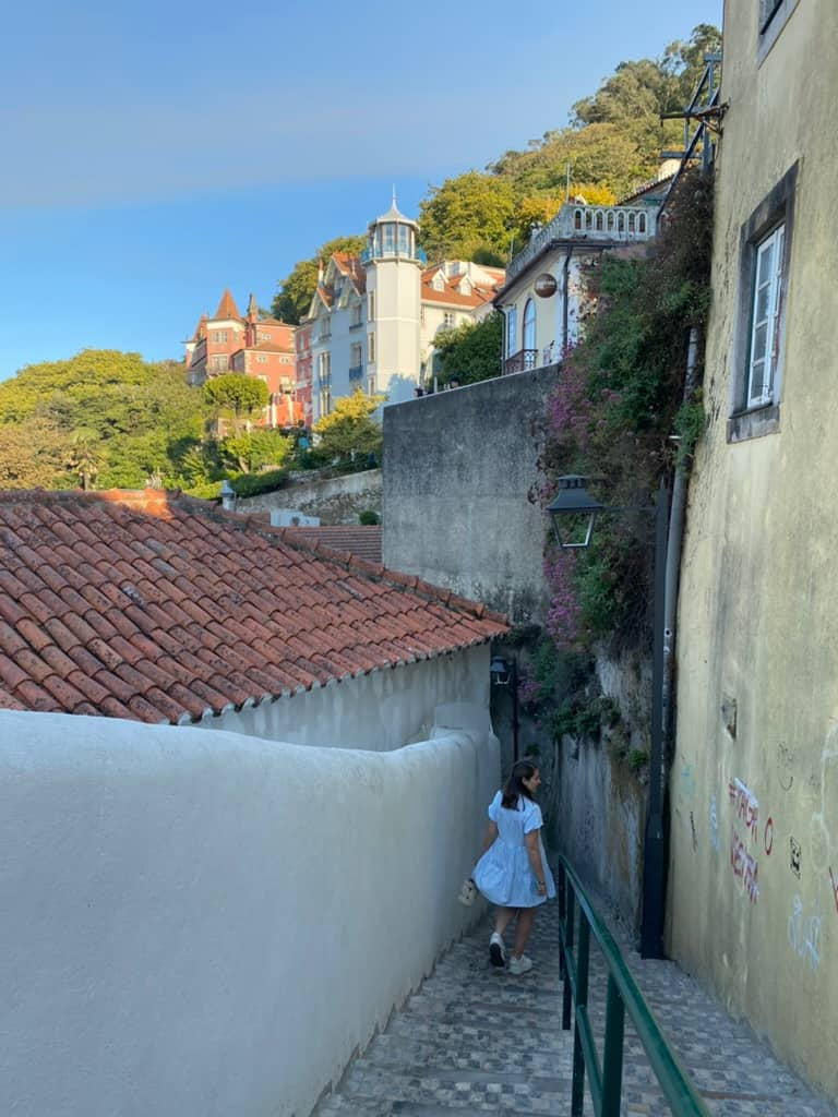 Woman walking through a narrow alleyway down a hill in Sintra, Portugal