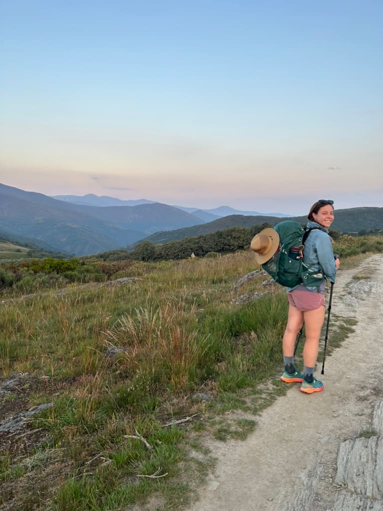 Female hiker smiling with mountains in the background on the Camino Francés route of the Camino de Santiago