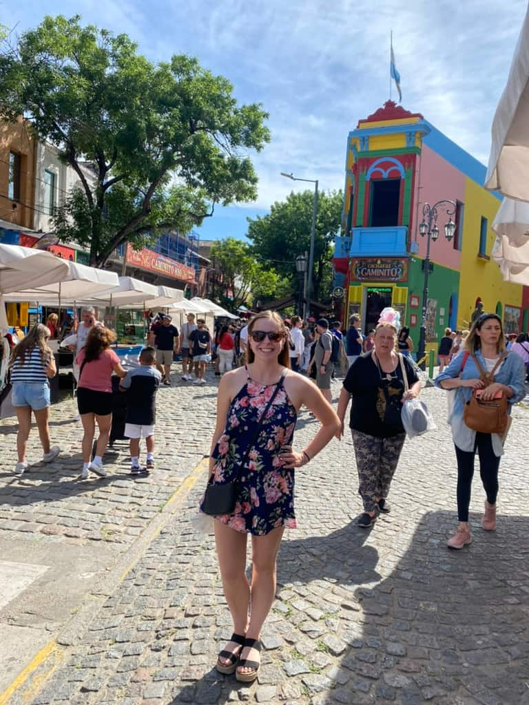 Woman standing and smiling in La Boca neighborhood of Buenos Aires with colorful buildings in the background