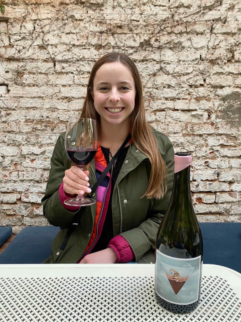 Woman smiling holding a glass of red wine in a courtyard at a restaurant in Buenos Aires