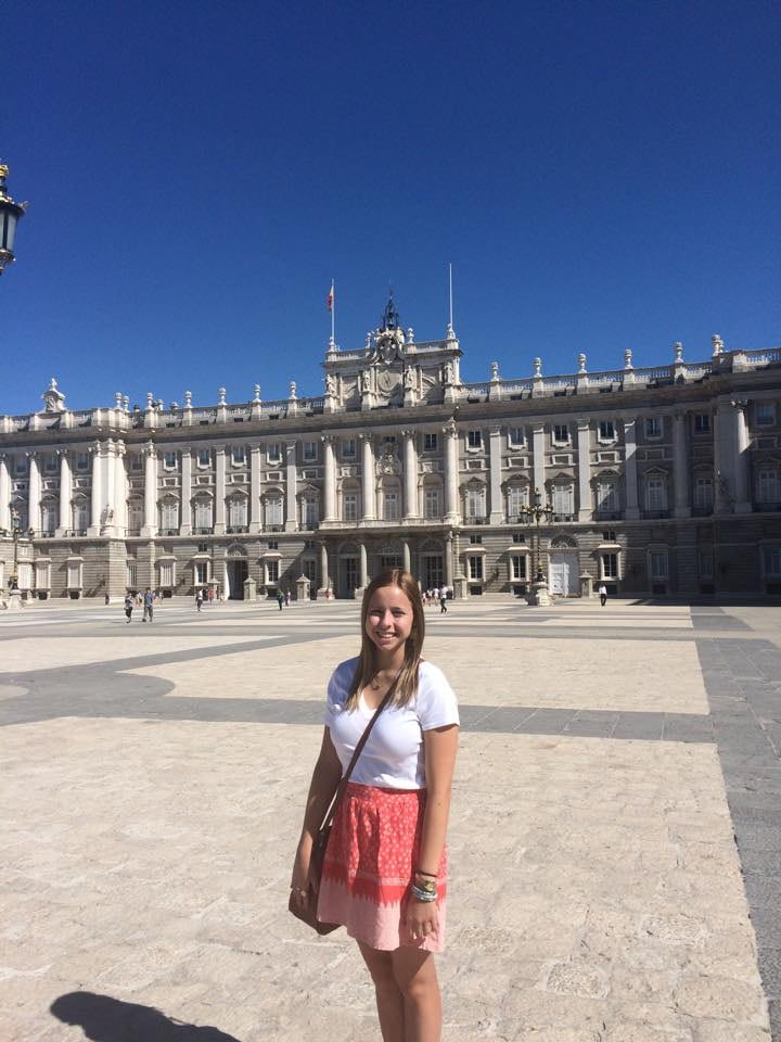 Young woman smiling in front of the palace in Madrid, Spain.