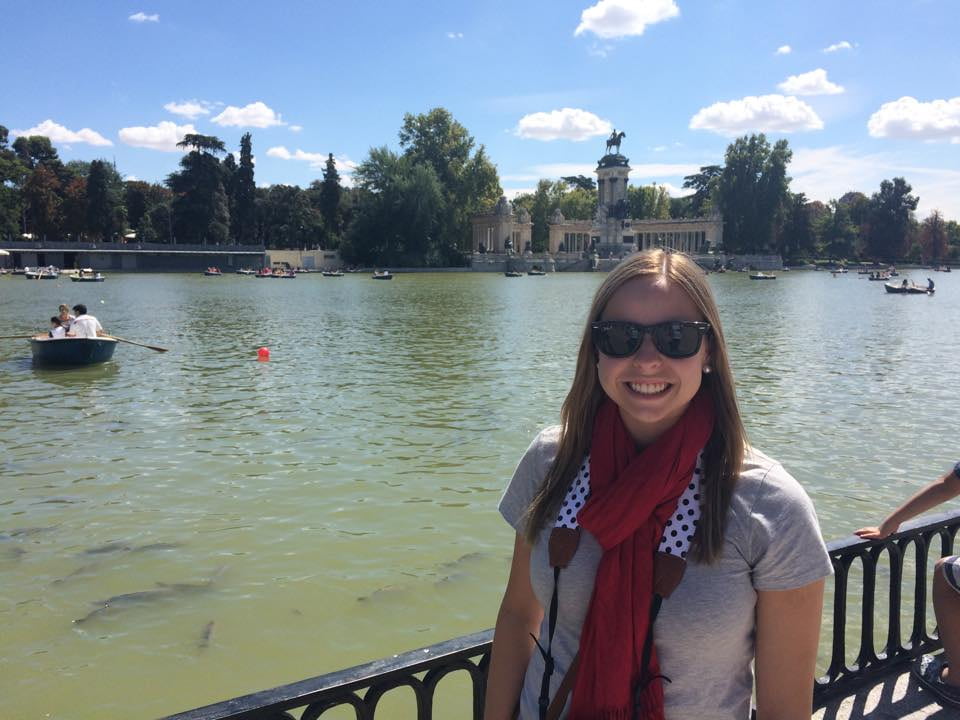 Woman smiling in front of a pond in Retiro Park in Madrid, Spain.