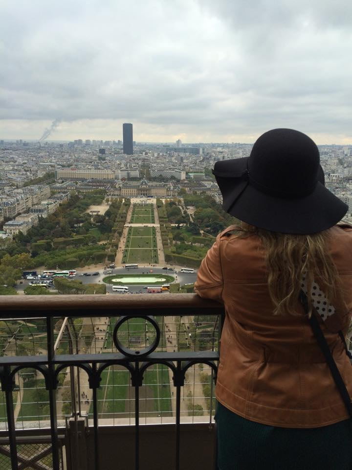 Woman looking out over a park in Paris from a balcony on the Eiffel Tower.