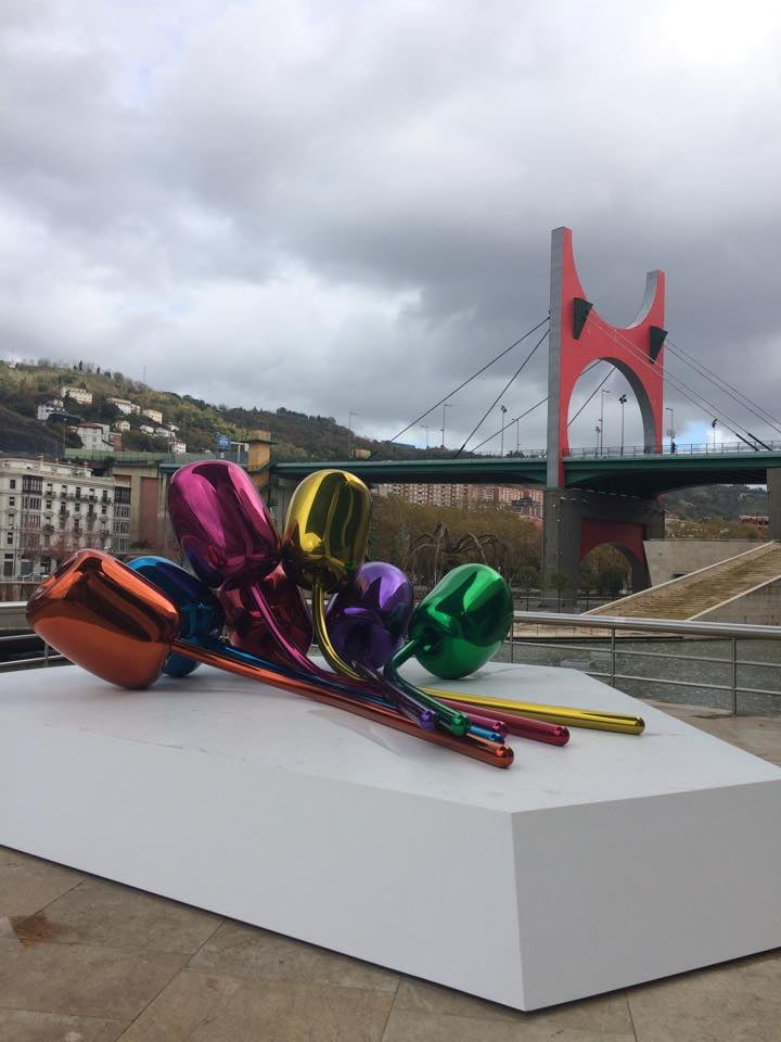 Colorful tulip art piece in front of a modern bridge in Bilbao.