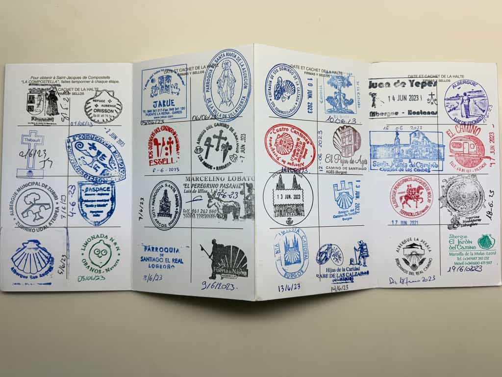 Pilgrim's passport book open showing many different stamps.