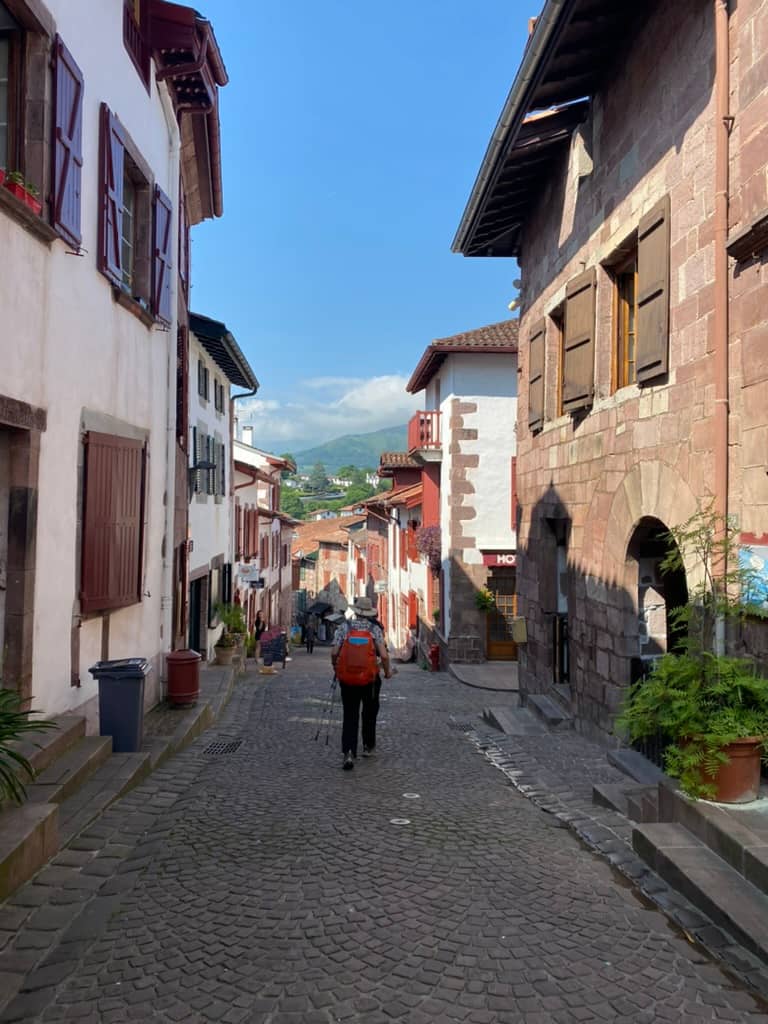 Camino hiker walking through the narrow cobblestone streets of Saint-Jean-Pied-de-Port, France