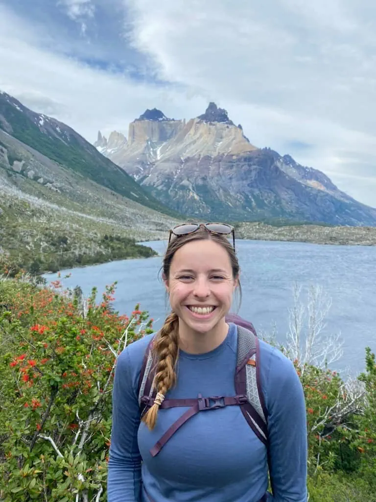 Mikala from The Unanchored Passenger smiling with a lake and mountain in the background at Torres del Paine National Park in Chile