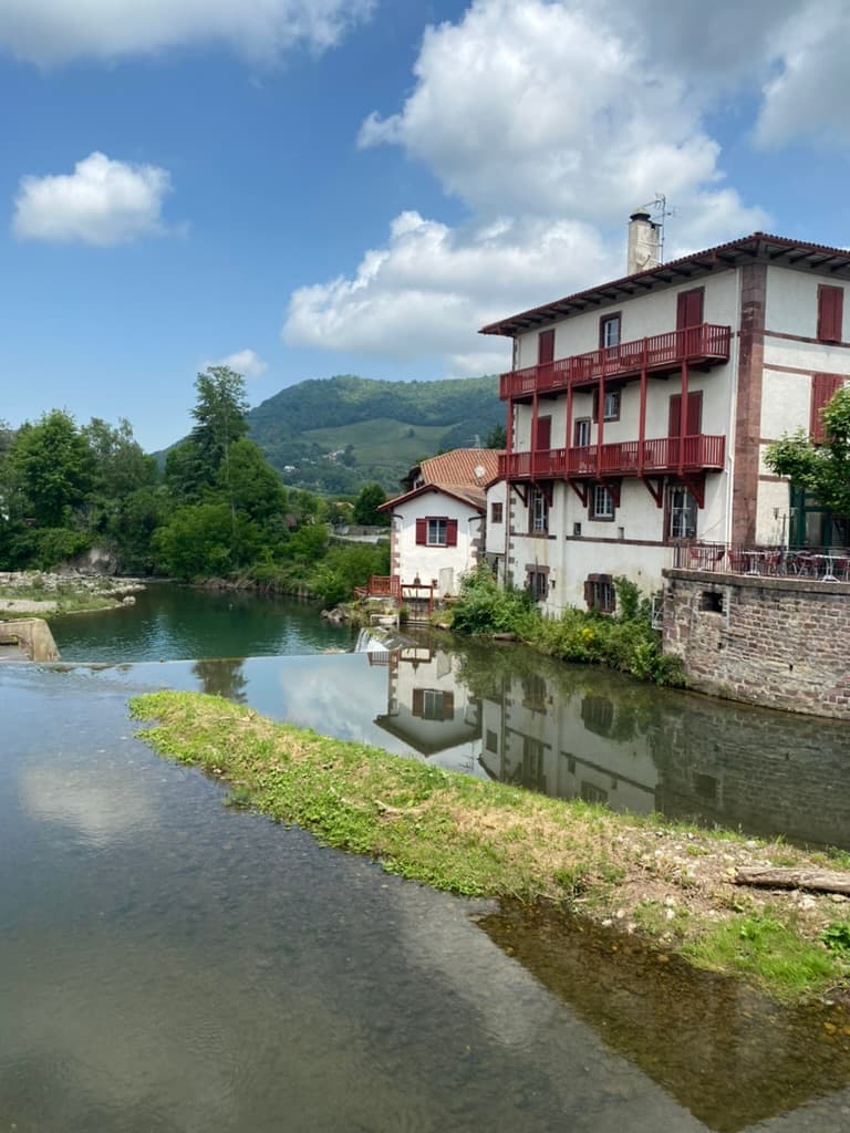 River flowing through Saint-Jean-Pied-de-Port with a quaint building on the river's edge.