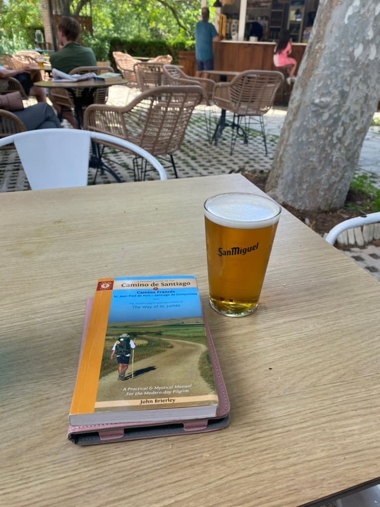 Camino Francés guidebook sitting on a table next to a beer at an albergue in Puente La Reina along the Camino Francés route of the Camino de Santiago