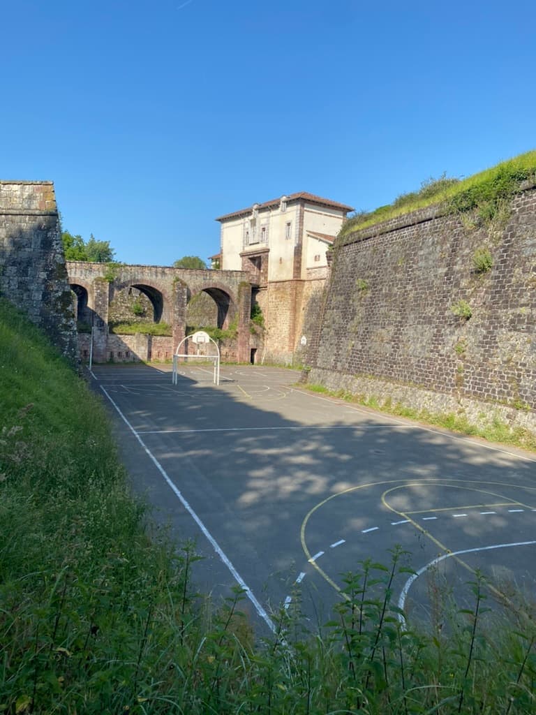 Back side of the Citadel in Saint-Jean-Pied-de-Port, France with a basketball court.