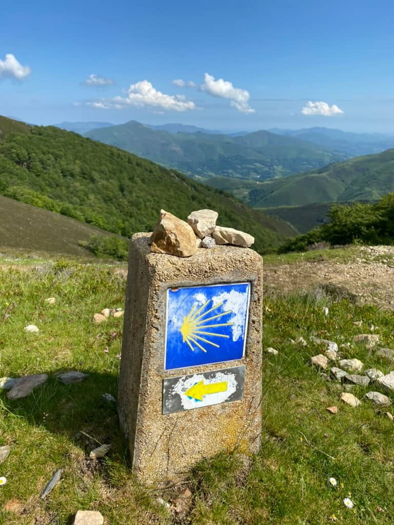 Stone Camino trail marker with a yellow shell symbol in the Pyrenees Mountains.