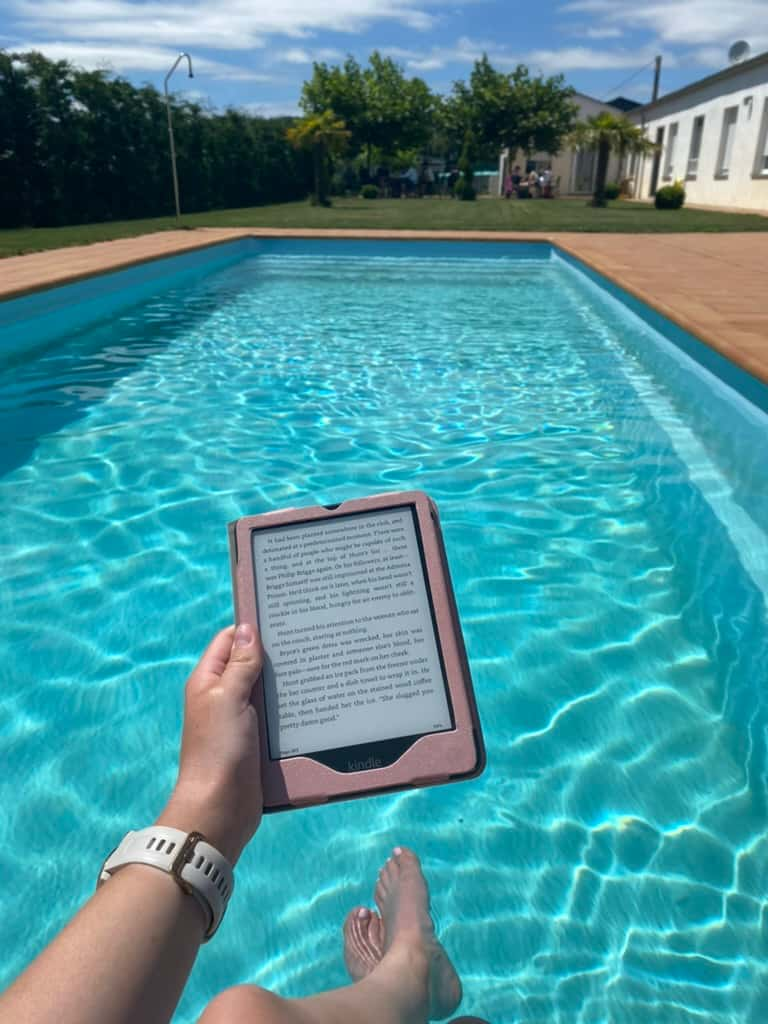 Hand holding up a Kindle over a pool at an albergue in Gonzar, Spain along the Camino Francés.