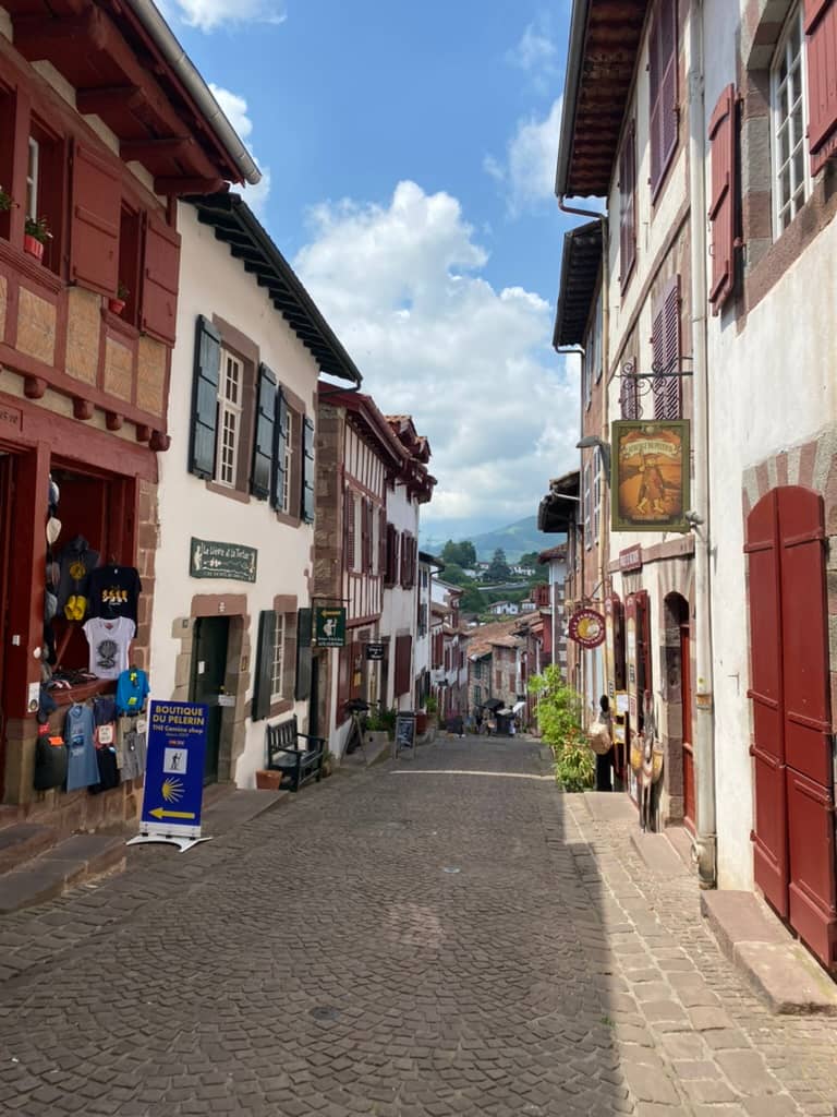 Narrow cobblestone streets of Saint-Jean-Pied-de-Port, France with a Camino de Santiago sign.