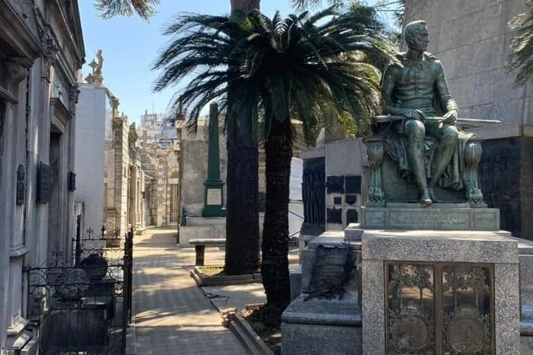 Recoleta Cemetery in Buenos Aires with mausoleums, a statue, and palm trees